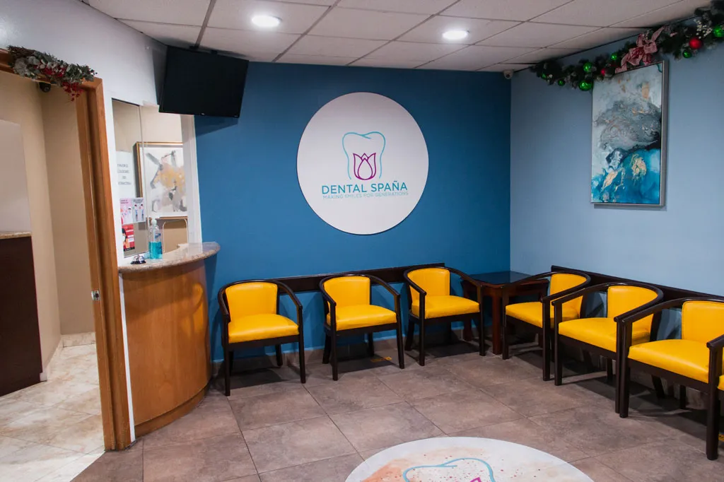 A dental clinic waiting room with a row of yellow chairs along a blue wall